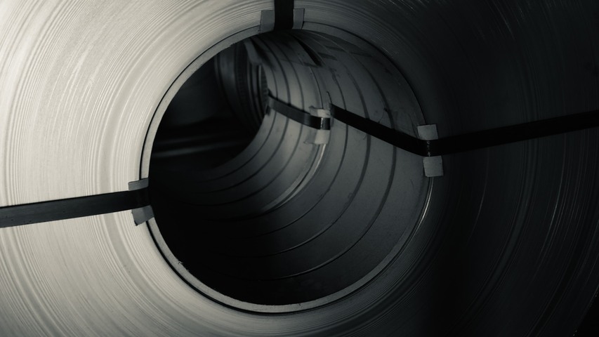 Close-up shot of a stainless steel strip coil from a perspective view of the inner core, showing metallic texture and industrial packaging straps.
